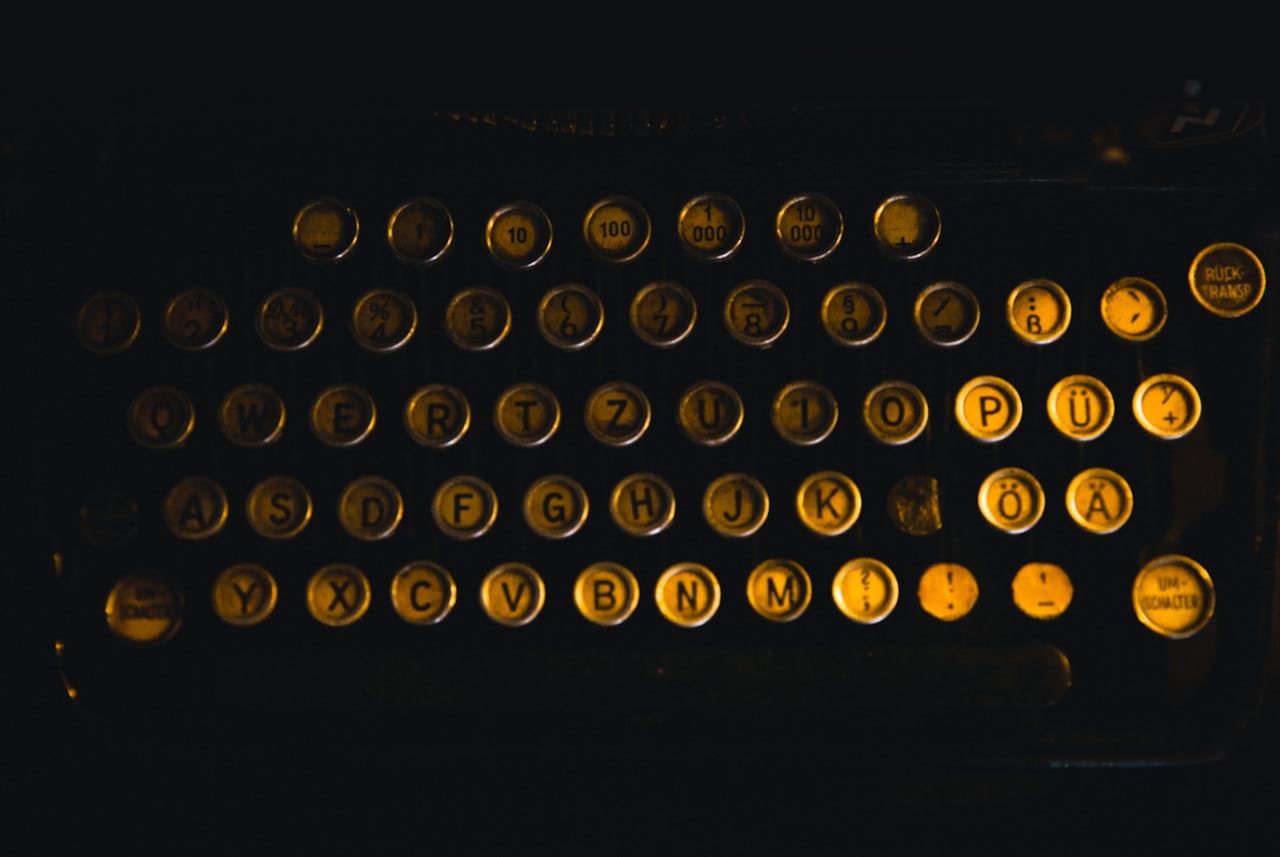 services-04 Close-up image of vintage typewriter keys with German letters in low light ambiance.