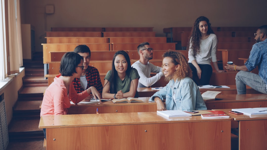 contact-img Multiracial group of university students are relaxing and chatting during break enjoying free time and communication. Wooden tables, attractive people and noteboks are visible.